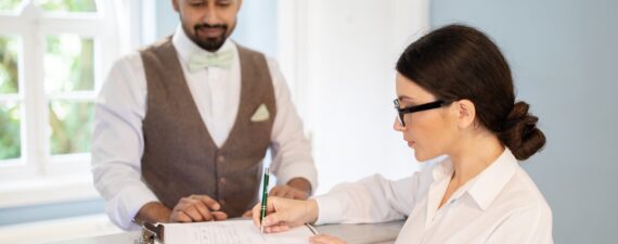 Businesswoman And Receptionist Filling Form Signing Papers Checking At Hotel