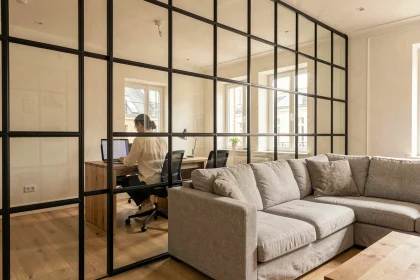 Verrière intérieure en acier noir séparant salon et bureau dans un appartement haussmannien rénové